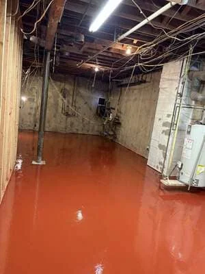 Bright red epoxy-coated industrial warehouse floor with exposed ceiling infrastructure