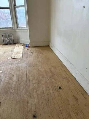 Interior room with prepared hardwood flooring and white drywall walls ready for finishing
