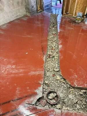 Red concrete floor with central gravel strip showing concrete repair and restoration work
