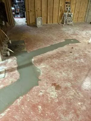 Self-leveling concrete being applied to interior floor in wooden structure