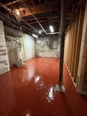 Freshly installed red epoxy floor coating in industrial basement space with exposed ceiling infrastructure