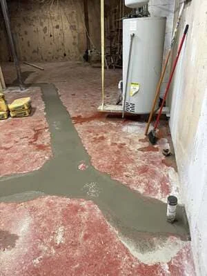 Flooded basement with standing water and damaged red flooring materials