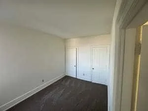 Renovated bedroom with dark hardwood floors and white closet doors